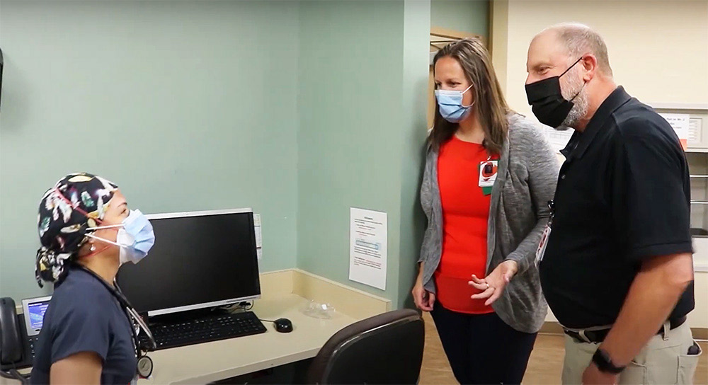 Three people in masks stand in an office