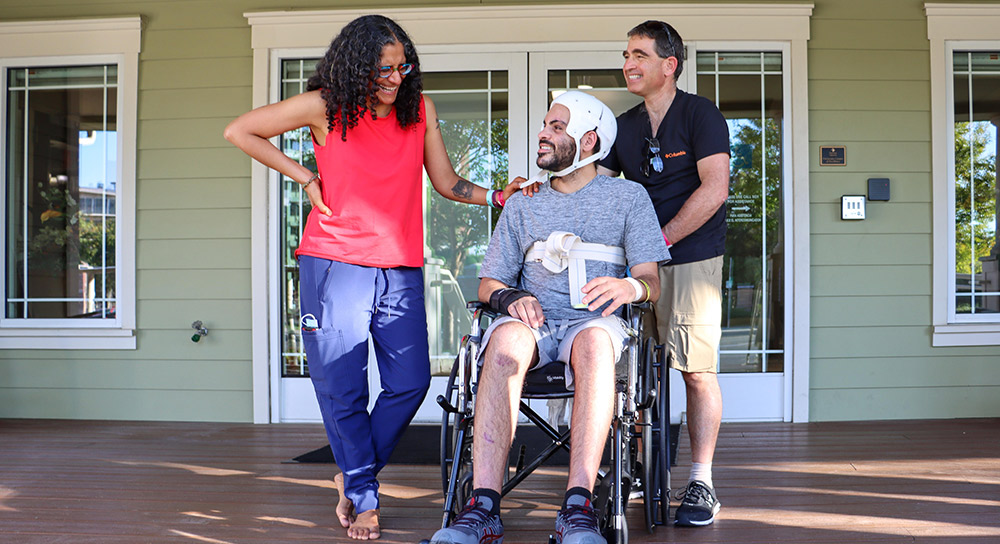 Parents stand next to their son who is in a wheelchair on the porch of Terry's House