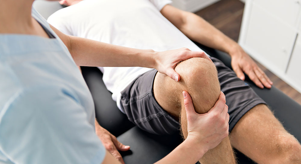 Close up of a healthcare worker examining a man's knee