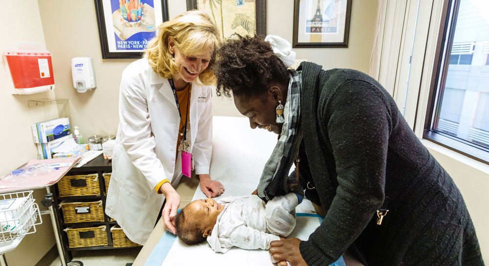Healthcare smiles as a woman tends to her baby on an exam table
