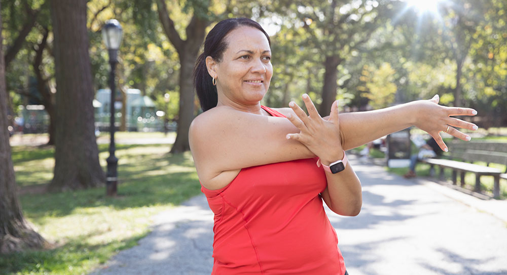 A woman stretches on a walking path