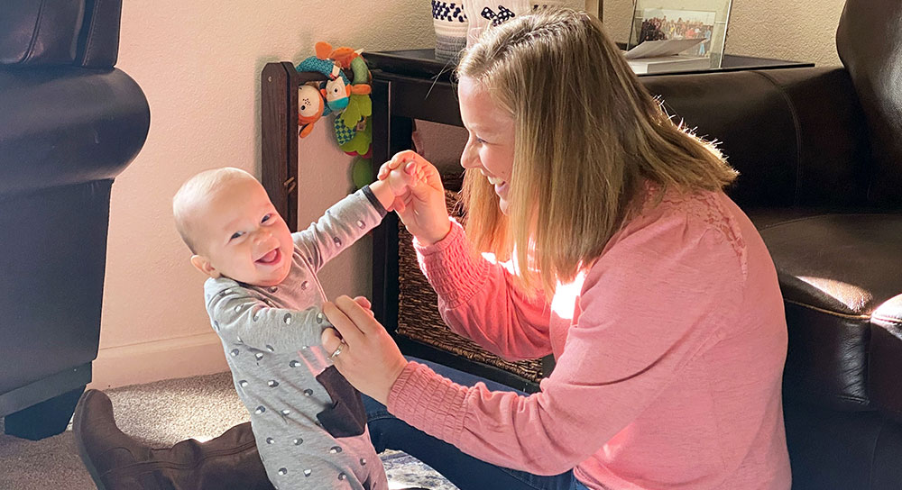 A mom plays with her smiling baby