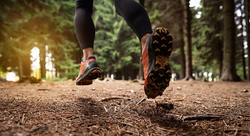 close up of a hiker with both feet off the ground on a hiking trail