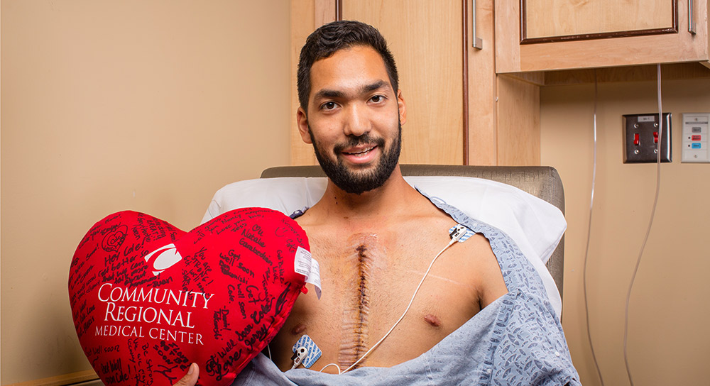 cardiac patient holding a red stuffed heart with well wishes written on it