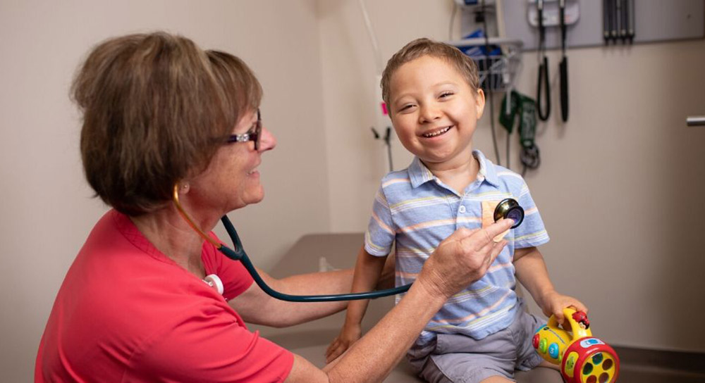A healthcare worker holds a stethoscope to Ezra Cambell's chest