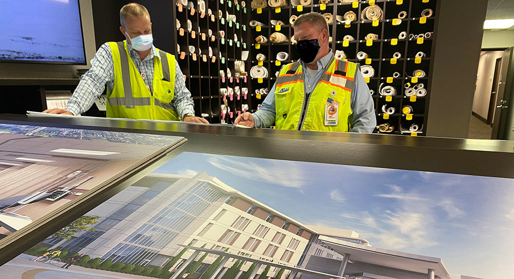 Two men in construction gear look at images of a building 