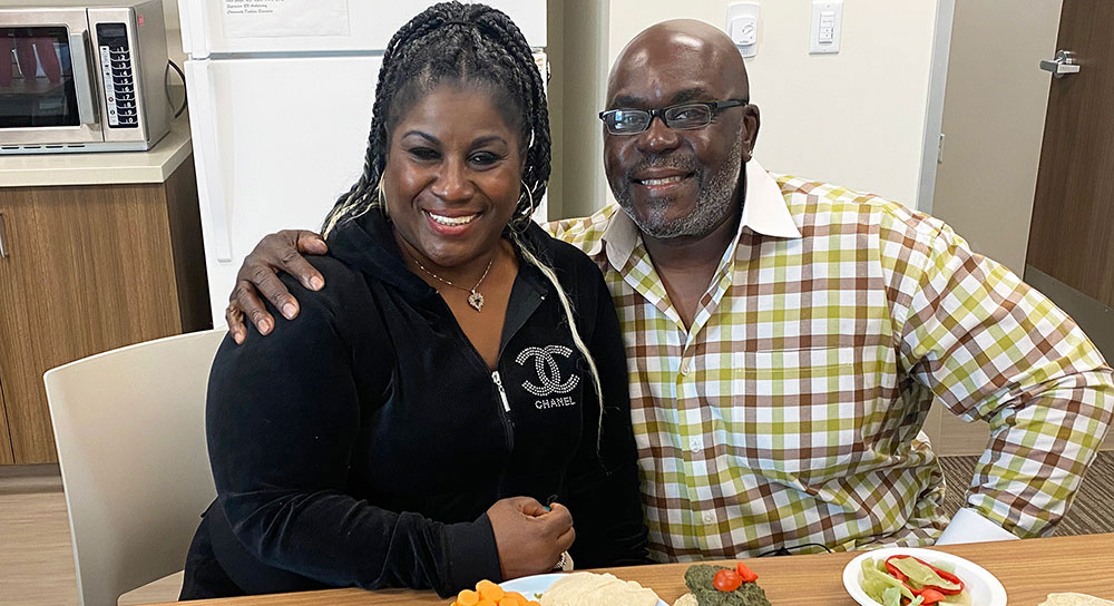Two adults sit at a table with healthy foods in front of them 