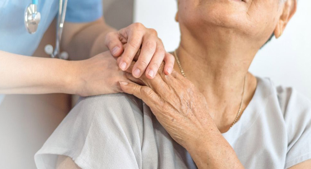 Close up of a nurse holding hands with an aging patient