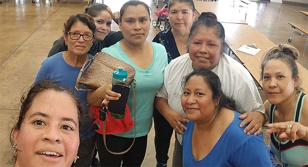 A group of 8 women smile at the camera after taking a dance class