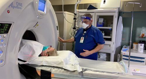a nurse stands near a patient in a CT scanner