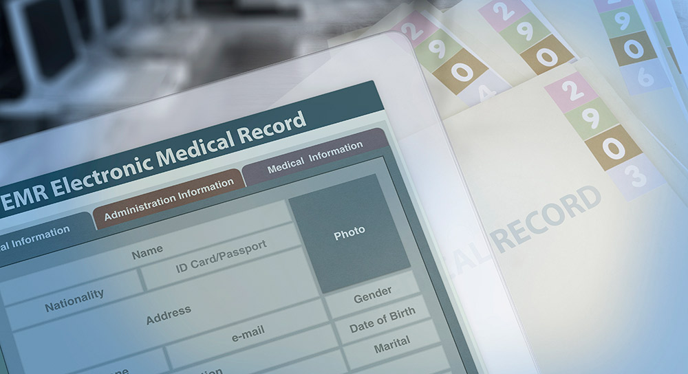 An image showing a tablet with electronic health information fields sitting on top of paper files