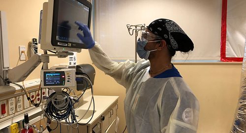 A student nurse looks closely at a monitor