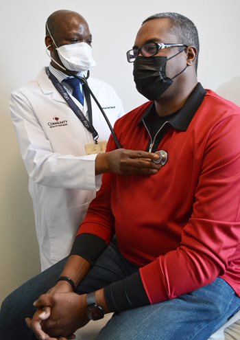Dr. Mohammed Bukari examines Calvin Mays Jr., who is sitting on an exam table