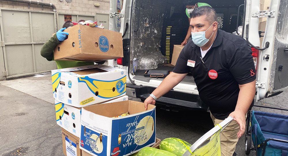 A man in a mask unloads food from the back of a truck