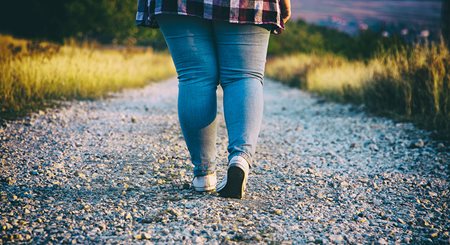 image of a woman from the back walking down a trail