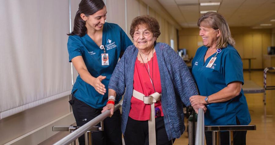 Rehab therapists help an older woman walk