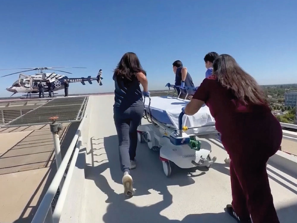 A trauma team rolls a gurney to a Skylife helicopter on top of a hospital