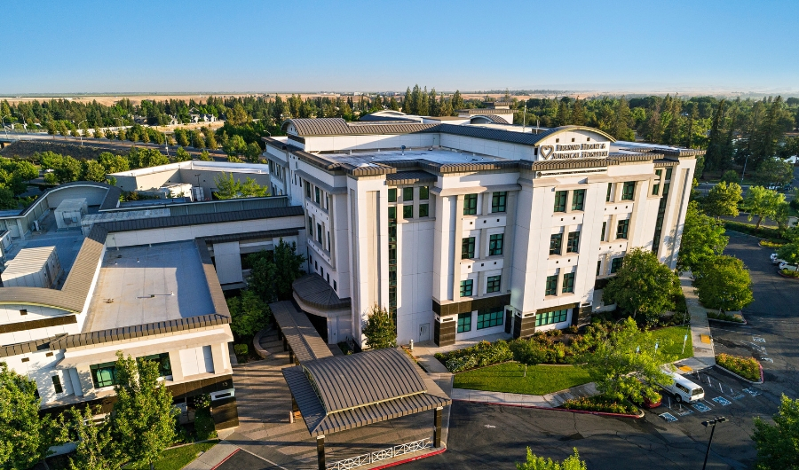 Exterior drone shot of Fresno Heart & Surgical Hospital in front of a blue sky