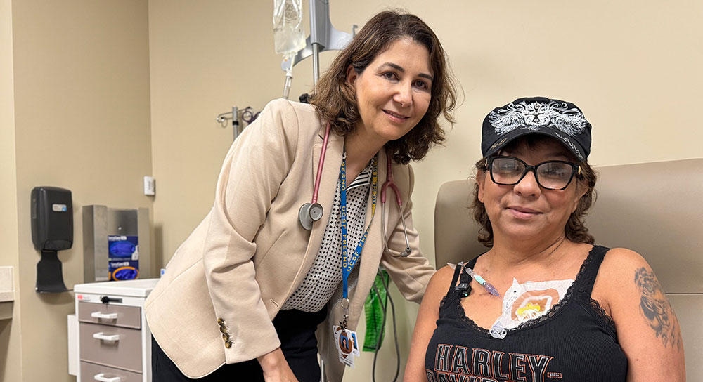 La Dra. Abdulhaq se para cerca de la paciente Christine Quintero, quien está realizando un tratamiento en una cama de hospital