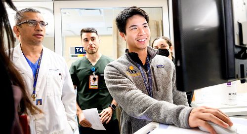 A group of medical residents stands around a computer screen 