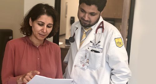 Dr. Haifaa Abdulhaq looks at a chart with a UCSF resident