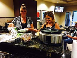 Two women work in the kitchen at Terry's House, preparing food.