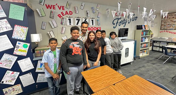 Teacher Robert Garcia smiles as he poses with six of his sixth grade students in his classroom at Birney Elementary.