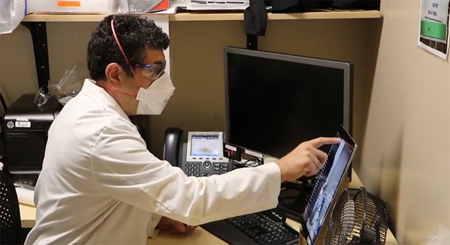 Dr. Afarian sits at a desk and checks electronic records