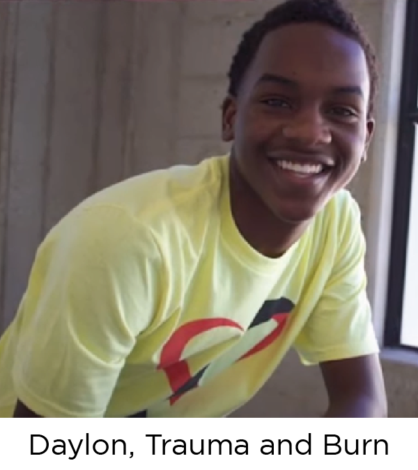 A teen boy, Black and wearing a yellow shirt, smiles at the camera.
