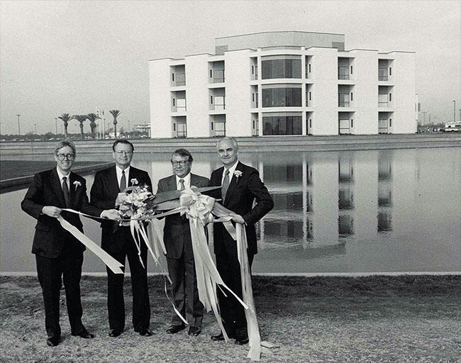 A black-and-white photo shows four men in suits at a ribbon cutting ceremony with Clovis Community Medical Center in the background.